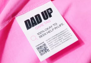 a white tag on a pink shirt with 'Dad Up' written on it