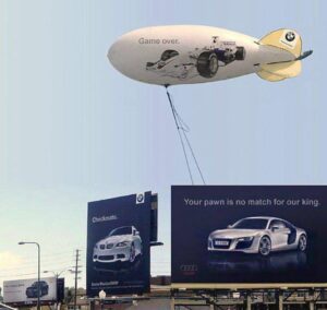 a blimp in the air with a picture of a car and billboards