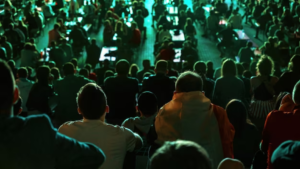 Crowd watching a performance with stage lights in the background.